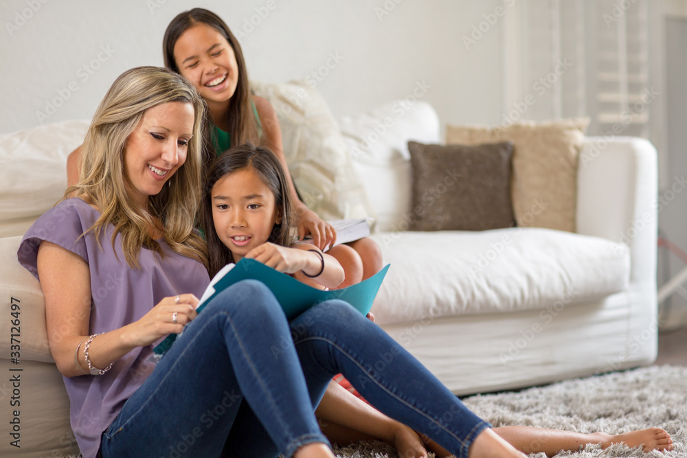 Mother Reading To Her Daughters And Helping Them With Their Homework Mother Reading To Her Daughters And Helping Them With Their Homework
