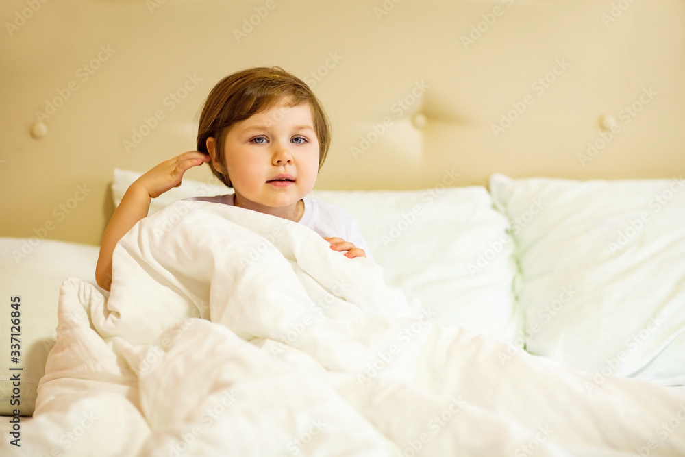 a sweet little girl with blue eyes ,lying in a white bed, under quarantine because of the covid-19 pandemic a sweet little girl with blue eyes ,lying in a white bed, under quarantine because of the covid-19 pandemic