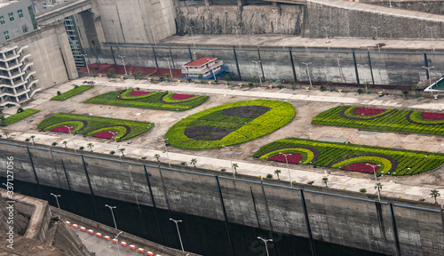 Three Gorges Dam, China - May 6, 2010: Yangtze River. Morning,  Green-red decorative garden of plants on beige concrete surface between 2 ship lift docks with parts of 2 boats visible. photo
