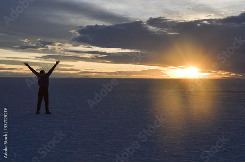 Man in in the Uyuni desert with arms up at the time of sunset