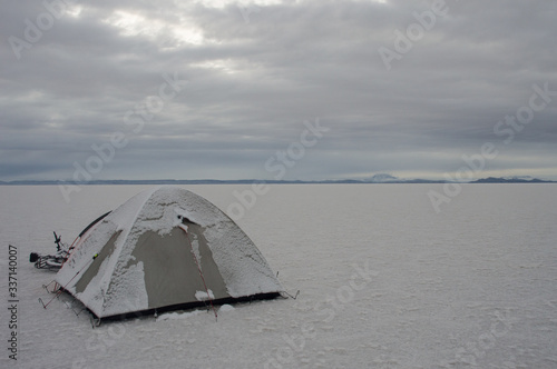 isolated and snow-covered tent in the salt desert in Bolivia
