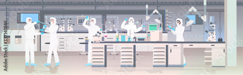 scientists team in hazmat suits holding test tubes working in medical lab mix race researchers making chemical experiments modern laboratory interior horizontal full length vector illustration