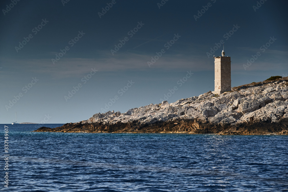 The lighthouse on the island in Croatia nearby Vis at sunset, a rocky coast, ladder to a beacon, a small cape