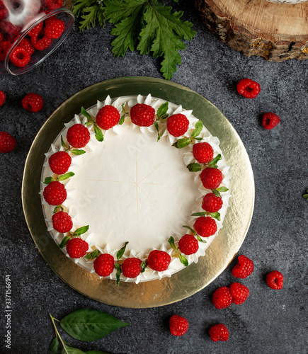 top view of raspberry cake decorated with white cream raspberries and mint leaves
