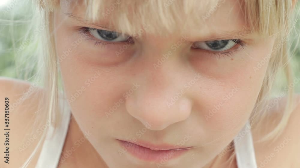 Angry frowning young girl with blond hair looking at camera close up face Angry frowning young girl with blond hair looking at camera close up face