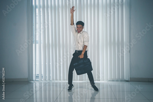 Cheerful man dancing with suit and briefcase