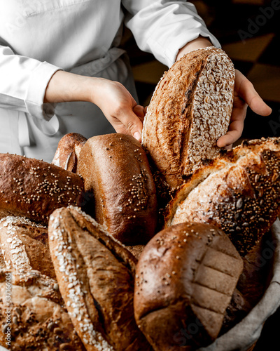 woman putting whole grain bread bun among other breads