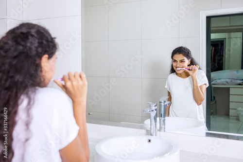 Cheerful woman brushing her teeth in bathroom