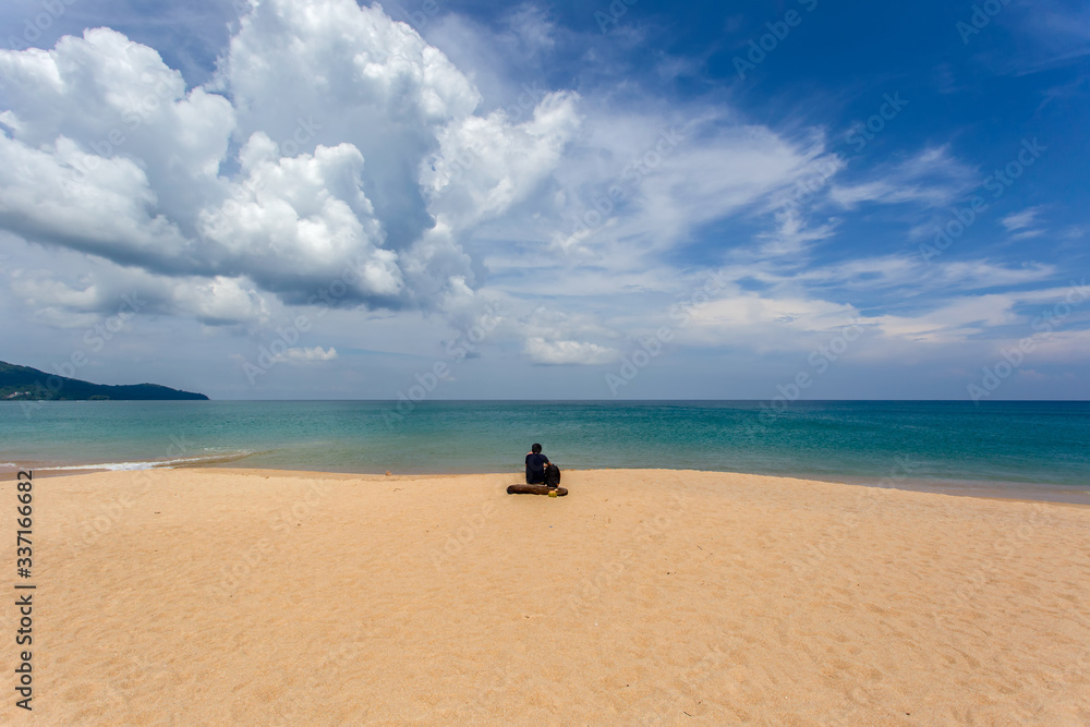 Young man sitting on the beach at Mai Khao Beach