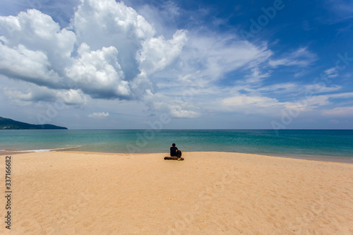 Young man sitting on the beach at Mai Khao Beach © Southtownboy Studio