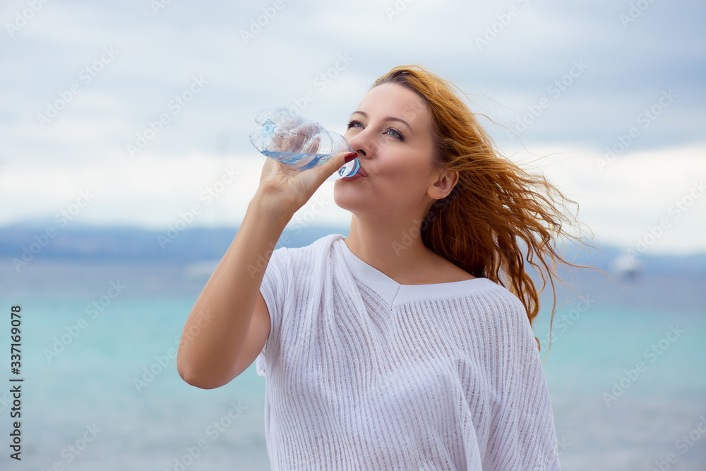 beautiful young woman drinking water in summer beach outdoor with sea background beautiful young woman drinking water in summer beach outdoor with sea background