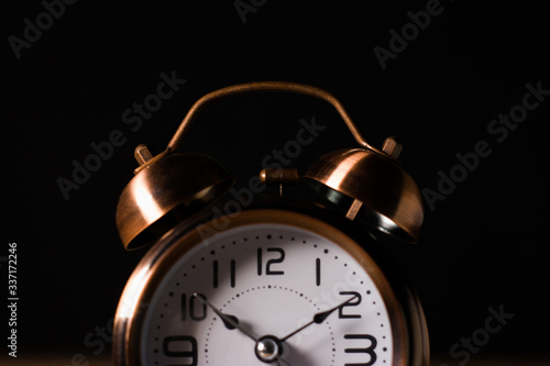 Antiguo reloj despertador de mesa marrón marcando a las 10:10 sobre un fondo negro
