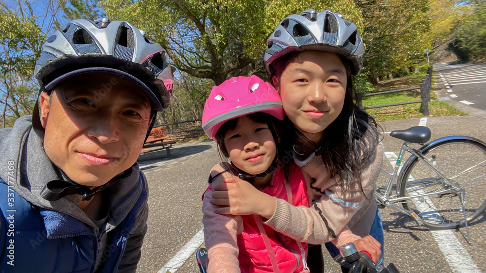 春の公園で自転車を乗っている家族三人 春の公園で自転車を乗っている家族三人
