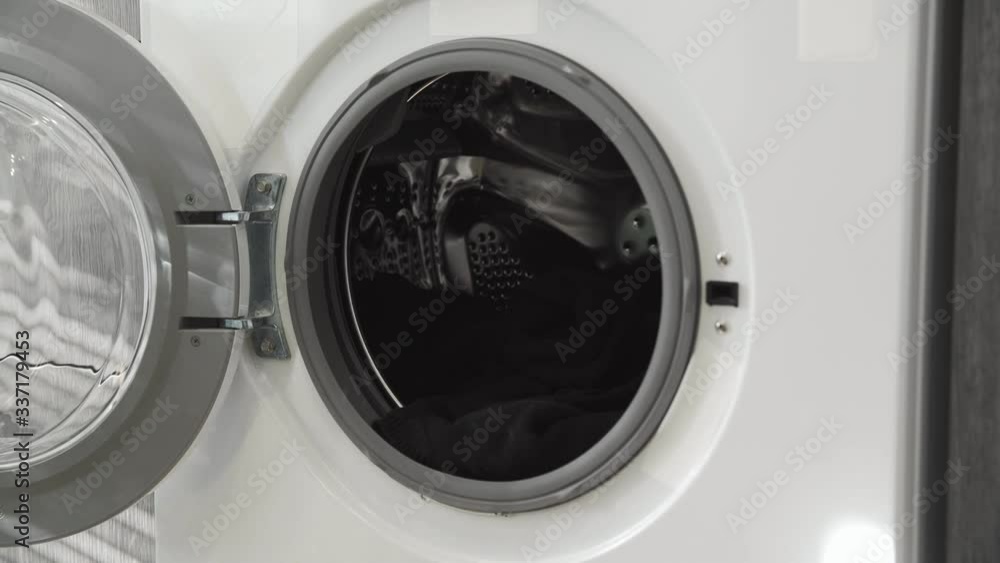 Male hand with married ring puts BLACK CLOTHES in laundry machine. Loading washing machine. Load clothes to washer machine. Load clothes laundry washing machine. Preparing laundry washing Male hand with married ring puts BLACK CLOTHES in laundry machine. Loading washing machine. Load clothes to washer machine. Load clothes laundry washing machine. Preparing laundry washing