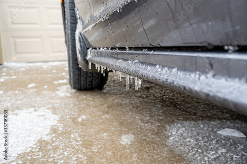 Freezing rain caused buildup of ice on concrete pavement and side runner of vehicle © Lost_in_the_Midwest