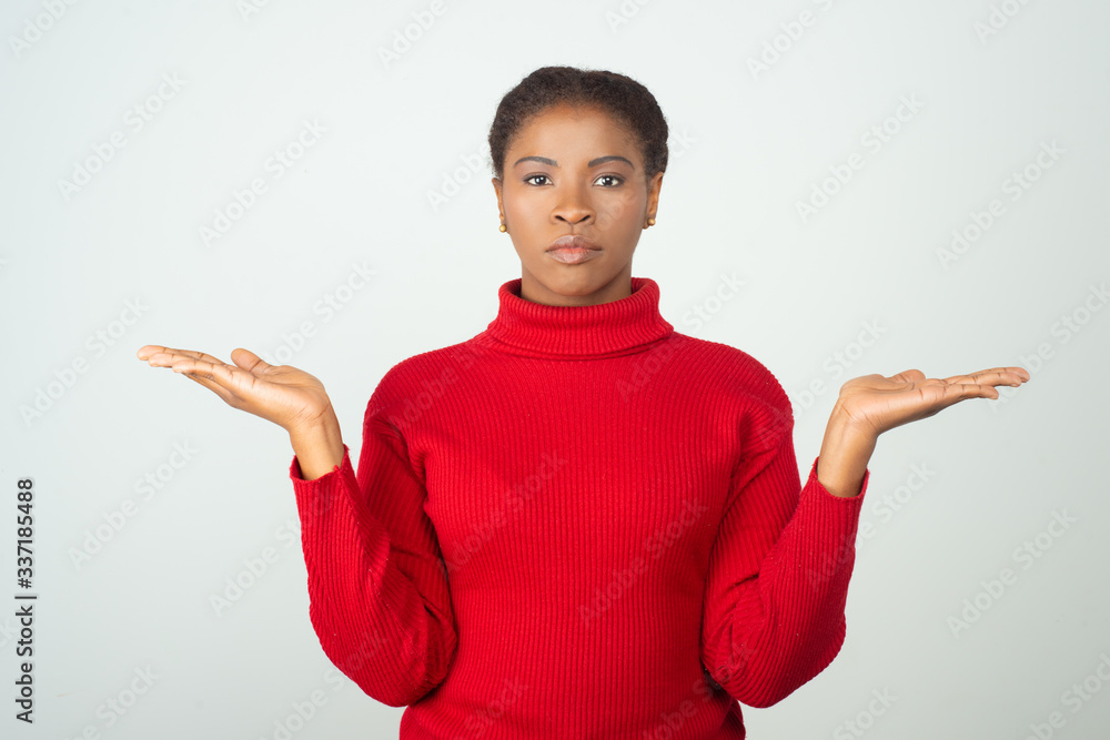 Serious calm female customer pointing both hands away. Beautiful young African American lady standing isolated over white background. Advertising concept Serious calm female customer pointing both hands away. Beautiful young African American lady standing isolated over white background. Advertising concept