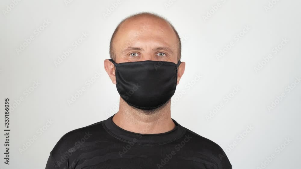 A young man puts on a mask and looks at the camera. isolated on white background healthcare and medical concept. Close up portrait. 4k A young man puts on a mask and looks at the camera. isolated on white background healthcare and medical concept. Close up portrait. 4k