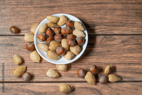 frutos secos mixto de almendras y avellana sobre un bowl de color blanco en una tabla marrón