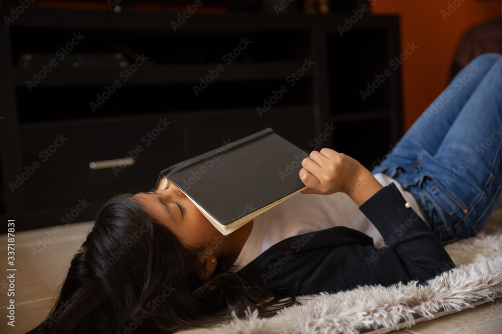 Obraz premium girl lying on a mat with notebook sleeping at home wearing white t-shirt and blue sweater and jeans coronavirus and pandemic quarantine in mexico