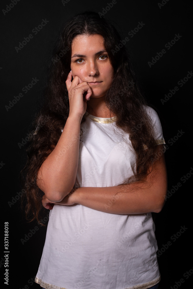 Young girl pensively looking. Hand on cheek. Black background. Human emotions Young girl pensively looking. Hand on cheek. Black background. Human emotions
