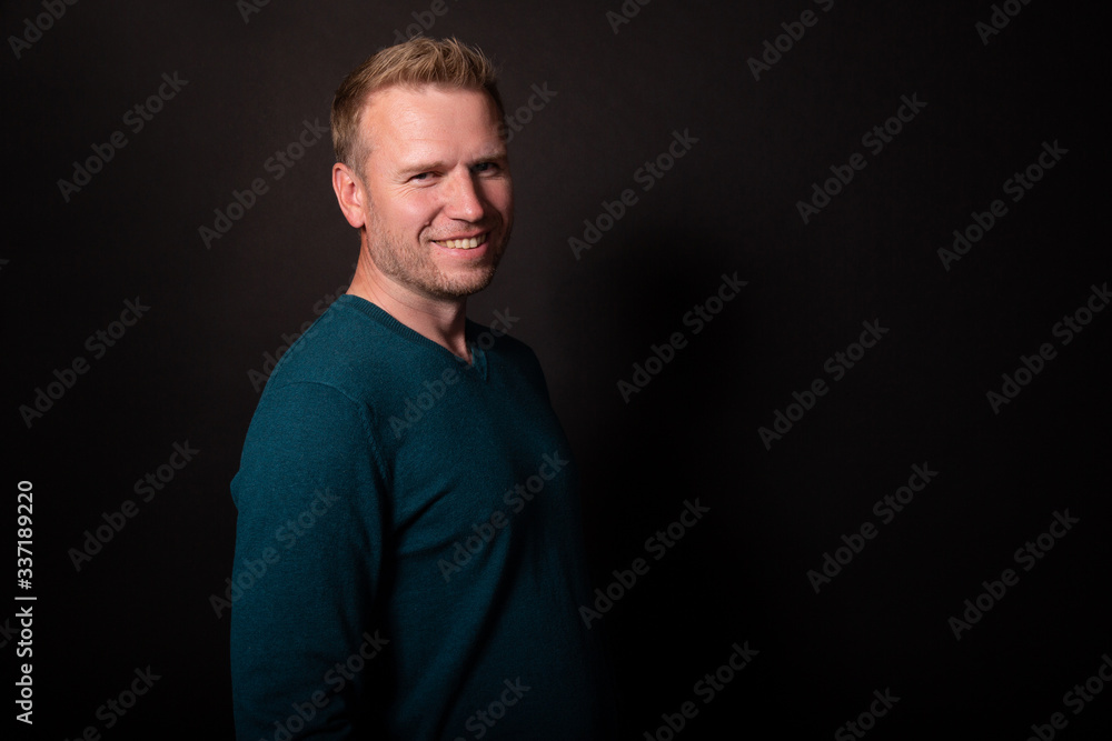 Attractive middle age man looks with charming smile. Isolated, black background Attractive middle age man looks with charming smile. Isolated, black background