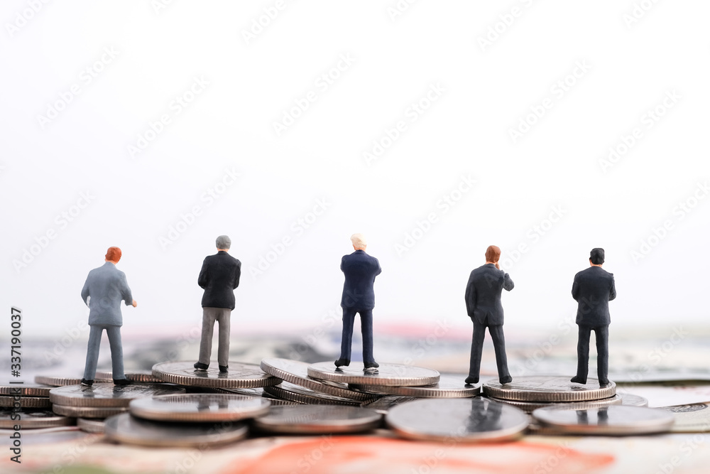 Miniature people : Many of businessman standing on the coin and banknote (US dollar, Singapore dollar) isolated on white background with copy space. Money, business finance, oil and stock concept Miniature people : Many of businessman standing on the coin and banknote (US dollar, Singapore dollar) isolated on white background with copy space. Money, business finance, oil and stock concept
