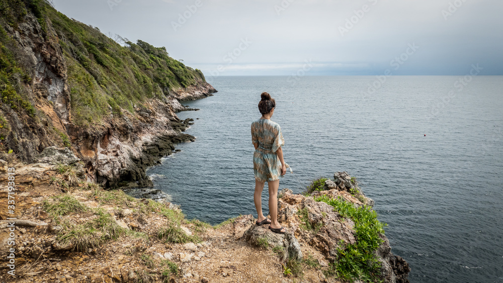 woman postting on the cliff, sea and blue sky in the morning.