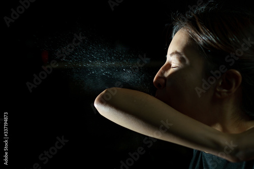 Woman coughing or sneezing in her elbow. Concept of stop spread of the virus. Spray infection photo