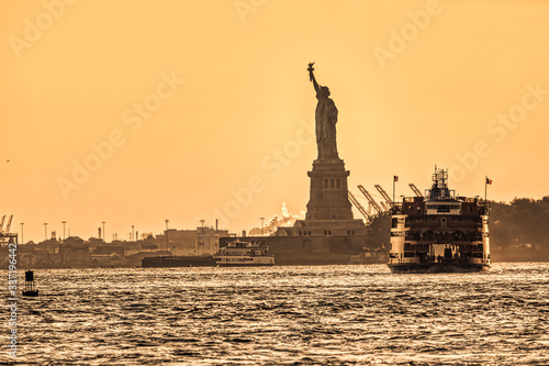 Water traffic on the Hudson River around Statue of Liberty at sunset while The Staten Island Ferry departing, New York photo