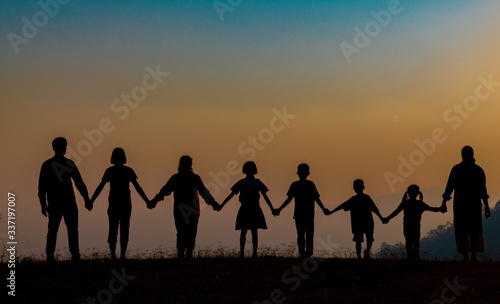 The shadow of a happy family holding hands in the meadow during sunset Happy family enjoying life together outdoors Round dance celebration ceremony