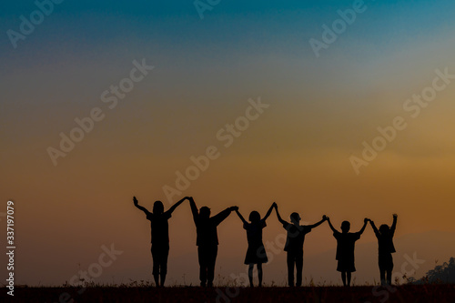 The silhouette of children jumping and playing happily in the mountains at sunset