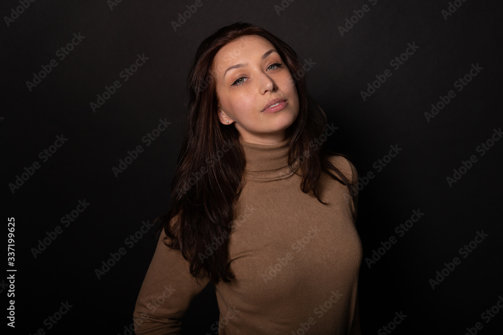 Attractive girl calmly looks at camera. Isolated black background