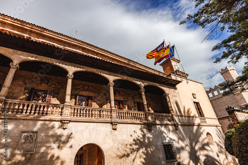 beautiful building of the Consolat de mar in Palma de mallorca with pine trees, canons and flags photo