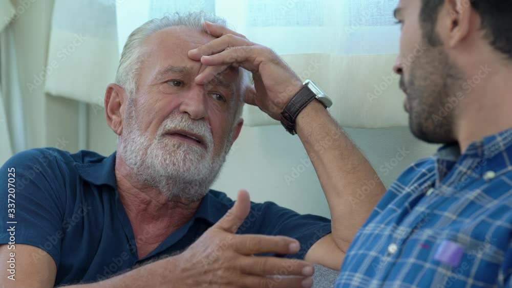  Happy family senior father talking and having fun with son on sofa in living room. Smiling old age dad spending time together with adult man son at home. Family bonding and good relationship concept