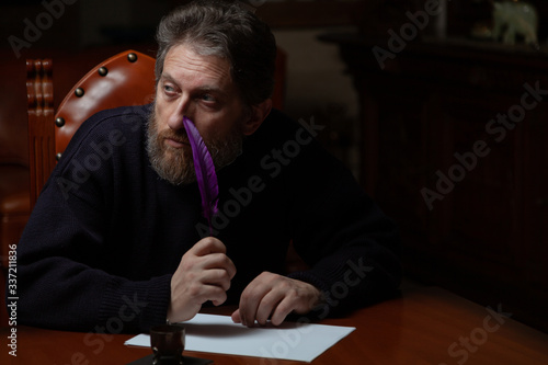 writer with beard writes on white sheet with goose feather