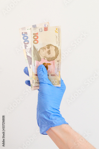 Ukrainian hryvnia banknotes in hand in surgical gloves. UAH banknotes. Covid-19 Coronavirus outbreak. Concept of stop and protect Covid-19 concept.