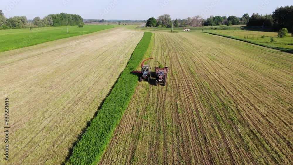 Two Old Soviet Tractors With Mower And Trailer Harvesting Clover Two Old Soviet Tractors With Mower And Trailer Harvesting Clover
