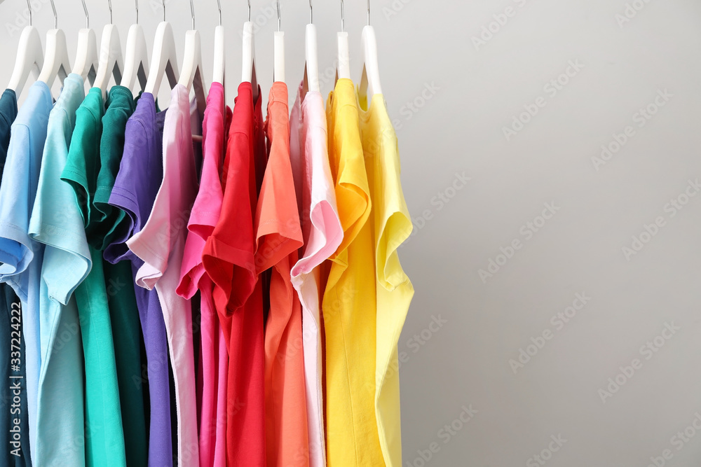 Rack with hanging clothes on grey background Rack with hanging clothes on grey background