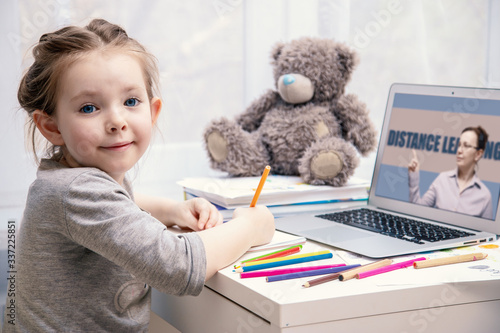 Little girl is engaged in online learning while sitting at home with a laptop with a pencil in her hands. Distant learning online education. Stay at home