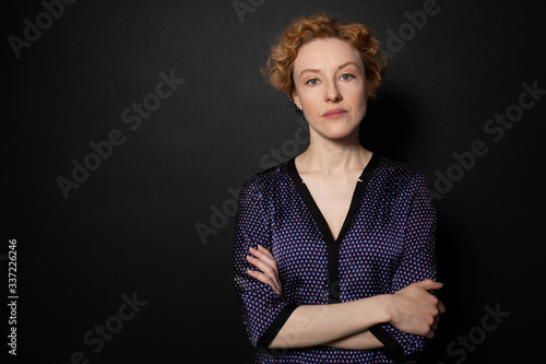 Beautiful woman standing with arms crossed, seriously looking . Black backgroung