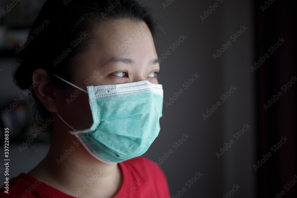 Quarantined asian woman wearing face mask stay at home and looking through the house window Quarantined asian woman wearing face mask stay at home and looking through the house window