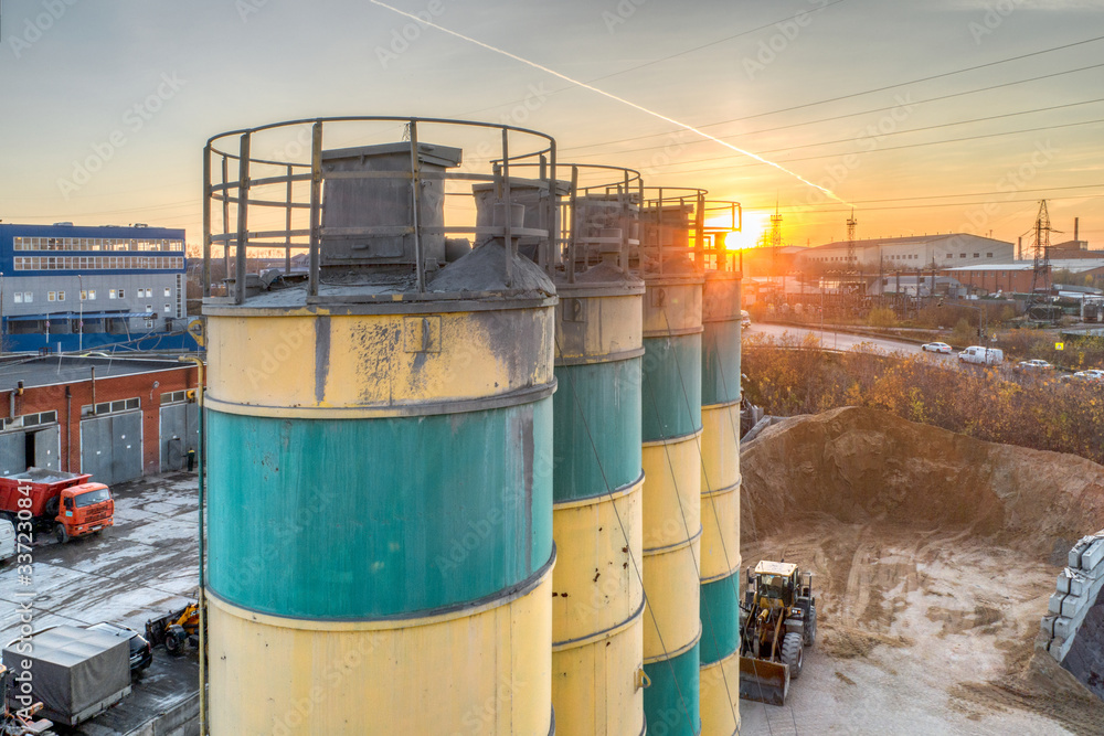 Obraz premium Silos for storage of cement aerial view. Evening shooting, the setting sun.
