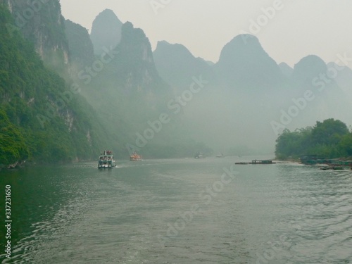 Lijiang River between Guilin and Yangshuo, China with boats cruising down the river with the misty karst mountains in the background.  © KingmaPhotos