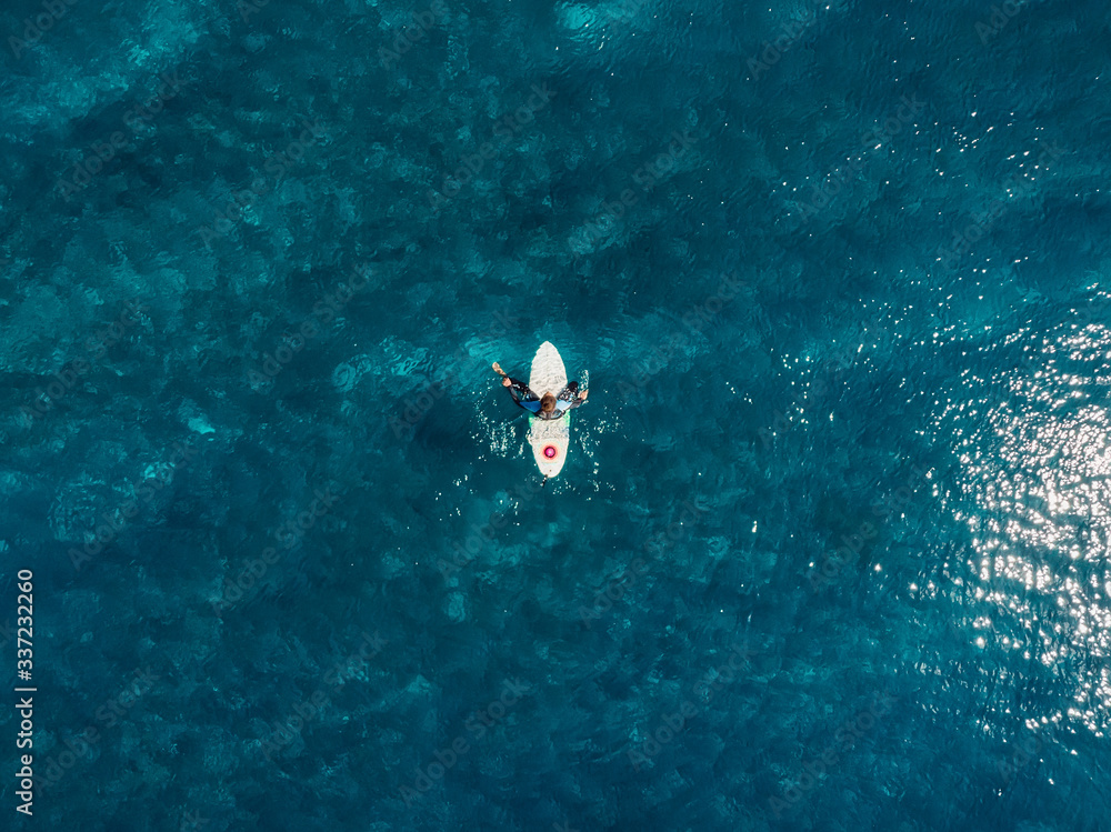Aerial view of surfer in blue ocean. Top view. Surfing in sea