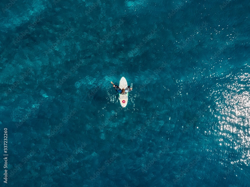 Aerial view of surfer in blue ocean. Top view. Surfing in sea Aerial view of surfer in blue ocean. Top view. Surfing in sea