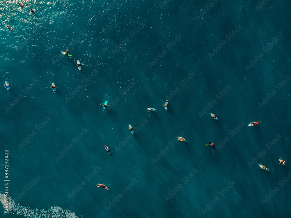 Aerial view of a lot surfers in blue ocean. Top view