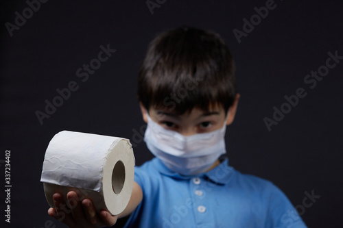 a child in a protective mask holding toilet paper napkins photo