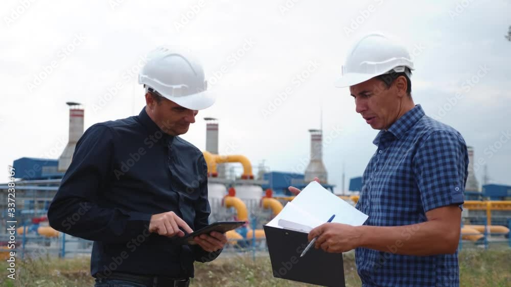 Teamwork. Two helmeted engineers are testing the operation of a gas processing plant. Teamwork Success and Victory Concept Teamwork. Two helmeted engineers are testing the operation of a gas processing plant. Teamwork Success and Victory Concept