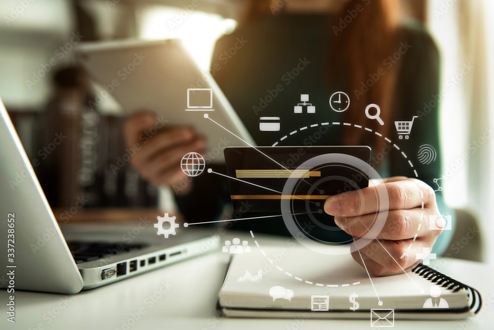 Hands holding credit card and using laptop in office home. Online shopping. Hands holding credit card and using laptop in office home. Online shopping.