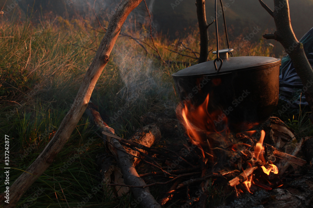 Tourist pot with shut lid is heated by the fire. Tourist pot with shut lid is heated by the fire.